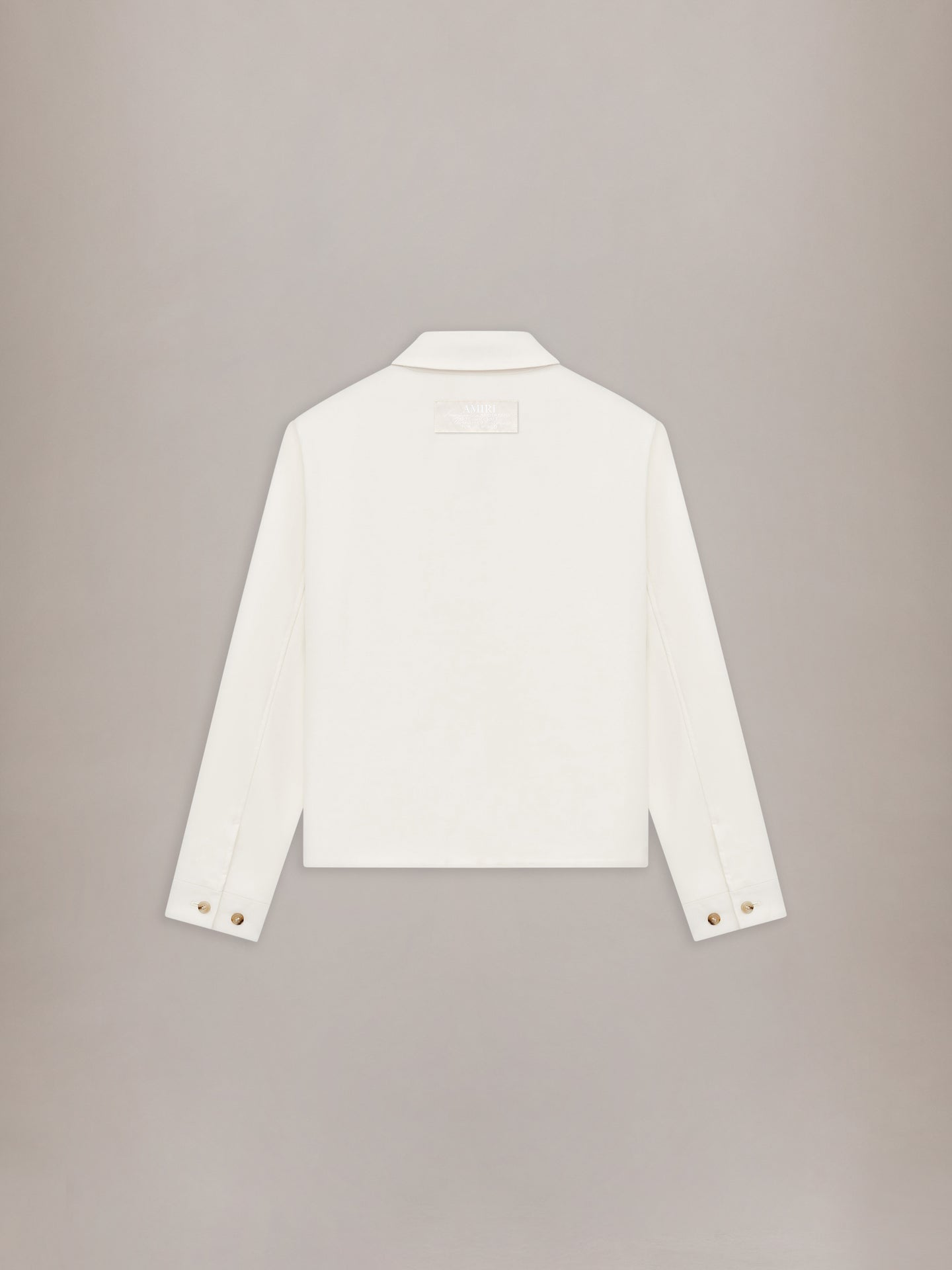 Cream-colored blouson jacket with collared neckline and gold button cuffs, displayed flat against neutral background.