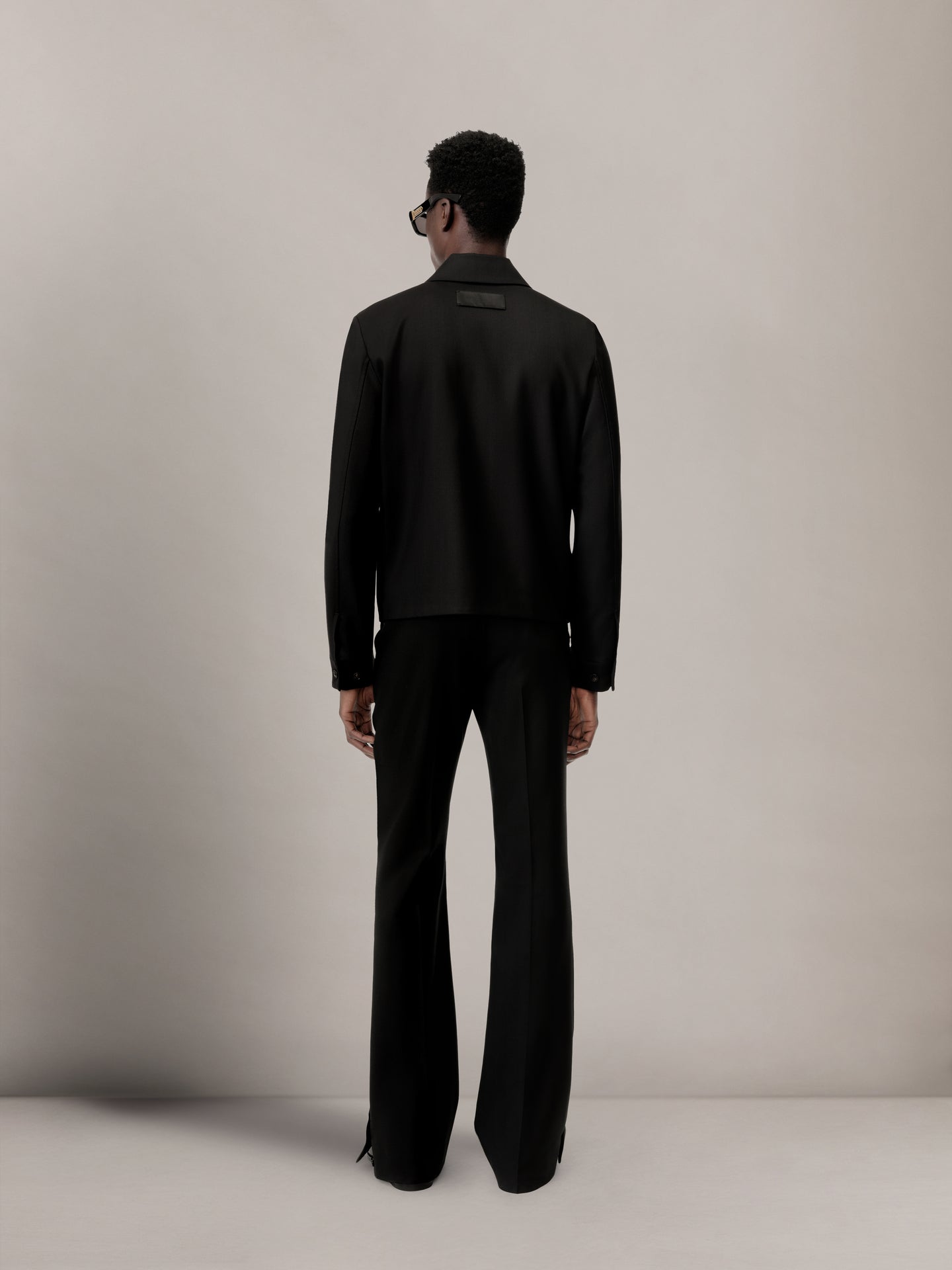 Black blouson jacket worn with matching black trousers, shown from back view.